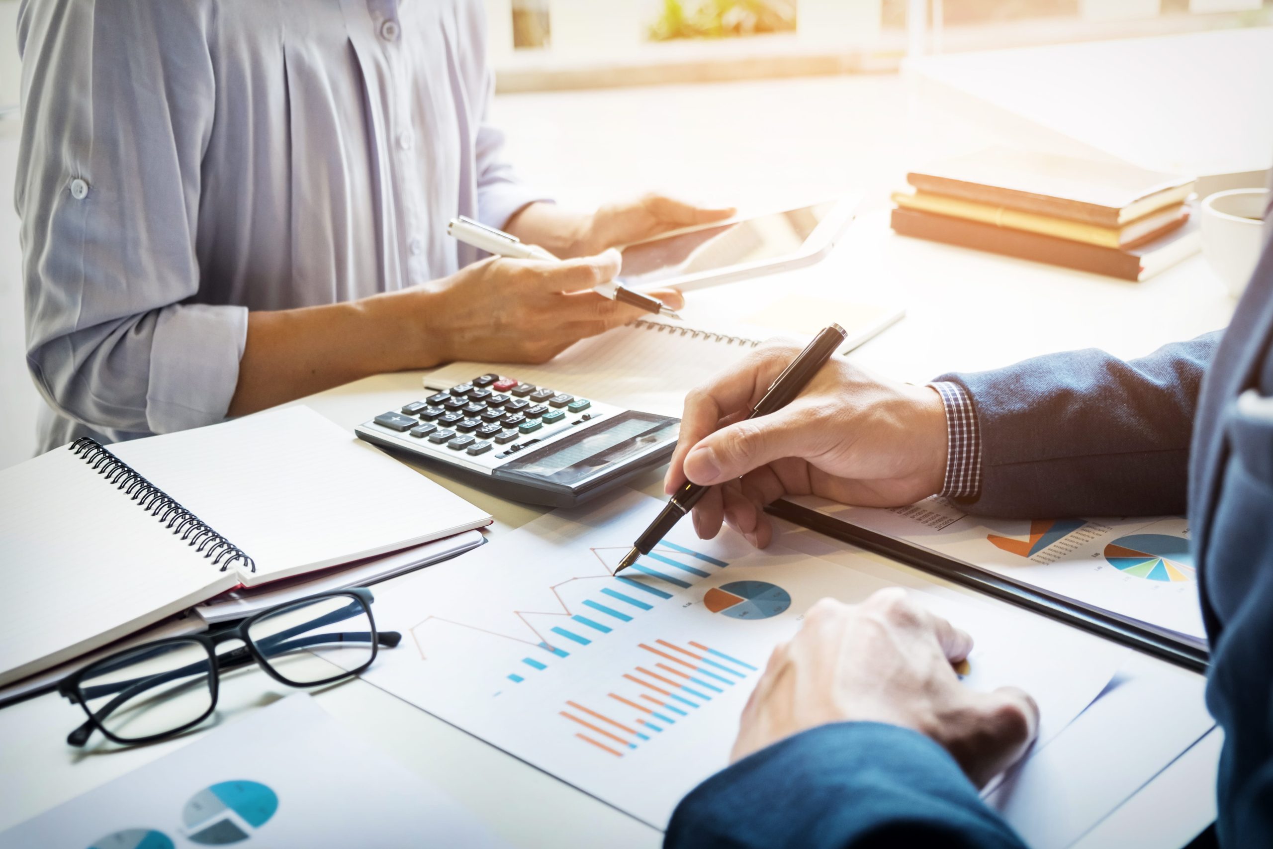 Adviser and client reviewing financial charts and a calculator